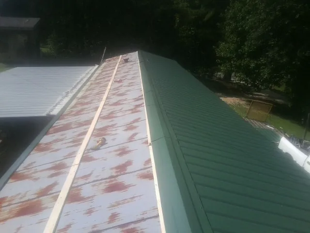 Old rusted panels beside newly installed green metal roofing — Wind Damage Roof Repair by Roofing Brothers in Milford Center