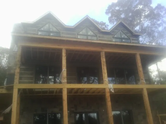 Dormers and porch framing on a large log home under construction — Roof Coating work by our crew in Milford Center