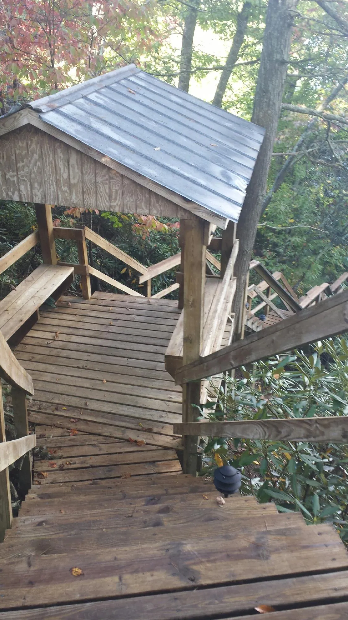 Metal roofed shelter over wooden steps on a wooded walkway — Skylight Repair & Installation work by our crew in Milford Center