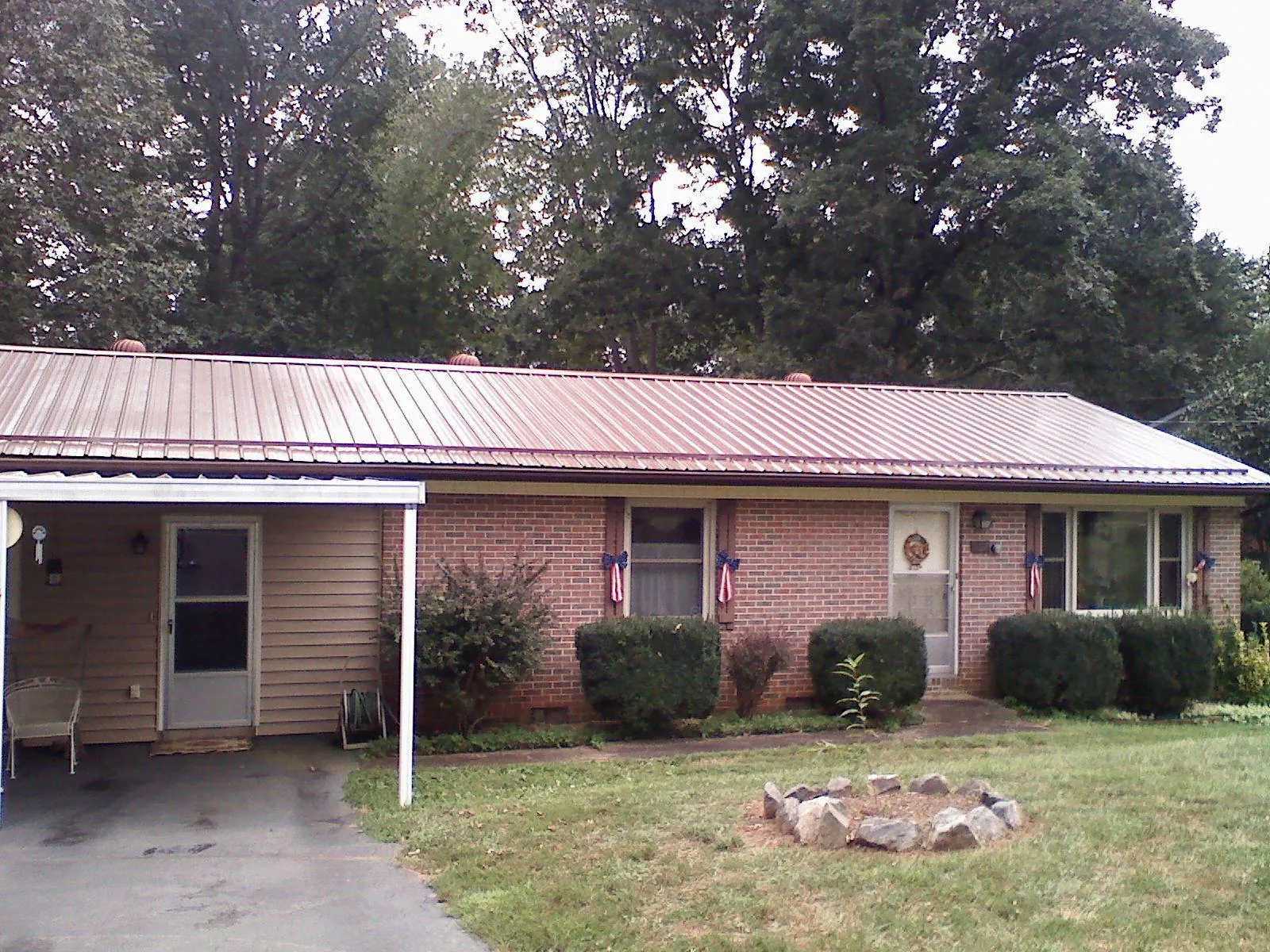 Bronze metal roof and carport on a brick ranch home — Roof Repair work by our crew in Milford Center