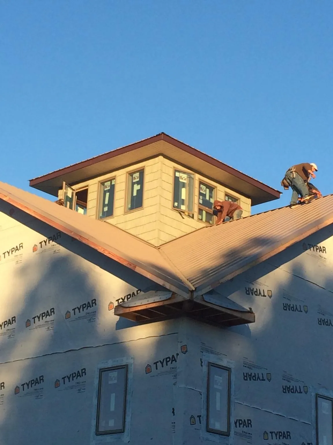 Roofers working around a rooftop cupola on a new metal roof at sunset — Roof Waterproofing in Milford Center by Roofing Brothers